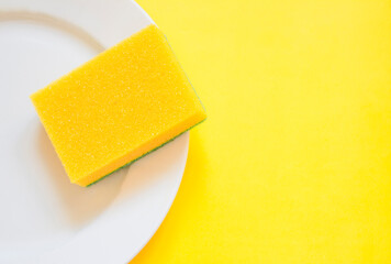 Yellow sponge on a white plate on a yellow background
