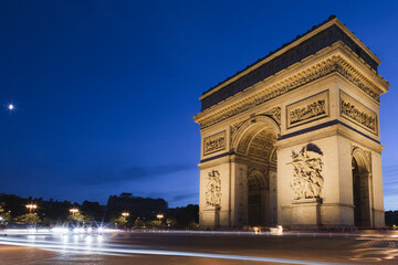 Fototapeta na wymiar Light trails left behind from buzzing motor traffic around the landmark Arc de Triomphe at night in Paris, France