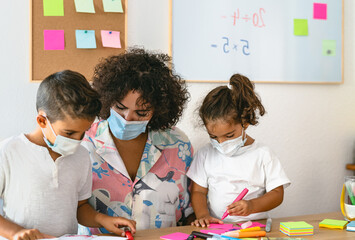 Teacher with children wearing face mask in preschool classroom during corona virus pandemic -...