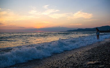 Obraz premium Amazing sea sunset on the pebble beach, the sun, waves, clouds