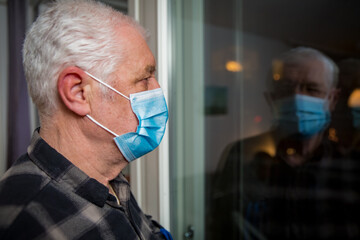 Senior man in protective mask staying home during pandemic lockdown. 