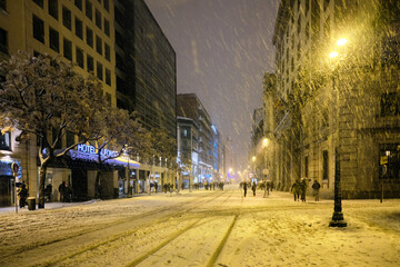 Street of a city at night on a snowy day.
