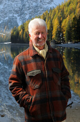 Ritratto di un uomo anziano sorridente con la giacca in riva al lago di Braies