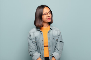young hispanic woman looking happy and friendly, smiling and winking an eye at you with a positive...