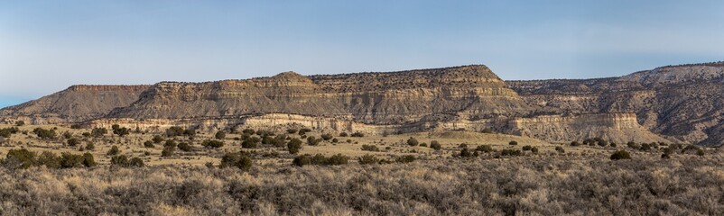 Fototapeta na wymiar Large panoramic shot of rocky mountain range with open field on clear day in rural New Mexico
