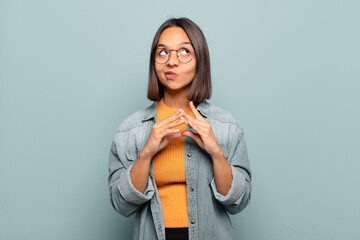 young hispanic woman scheming and conspiring, thinking devious tricks and cheats, cunning and...