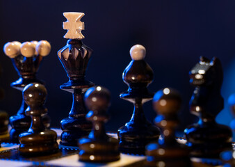 Chess board with chess pieces on blue background. Concept of business ideas and competition and strategy ideas. Black king and figures close up.
