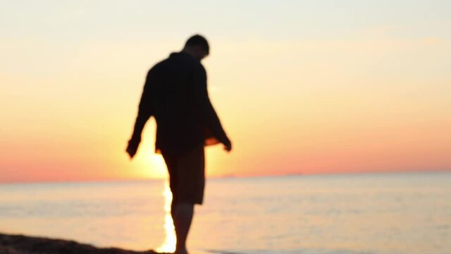 young happy man walking by sandy sea beach on sunrise