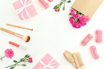 Hair dresser frame made of pink roses with hairbrush, tassel and gifts on white background. Flat lay