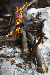 Traveler's forest ax close-up against the background of a divorced fire, close-up.