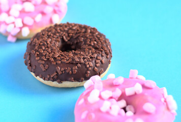 Three cocholate and sugar doughnuts diagonally. Selective focus. Blue background. Isolated donut. Colorful background.