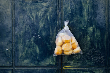 bread rools in plastic bag hanging on green door