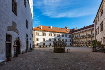 Fototapeta na wymiar Jindrichuv Hradec, Czech Republic - September 26 2019: The courtyard of the Renaissance castle with white facade and arcades. Water well in the middle. Sunny day with blue sky.
