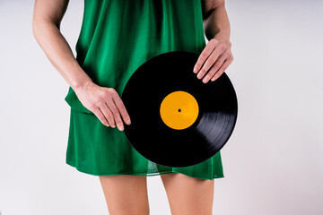 Unrecognizable woman portrait cutout holding a vinyl record dressed in green dress and on white background