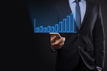 Business man holding holographic graphs and stock market statistics gain profits. Concept of growth planning and business strategy. Display of good economy form digital screen.