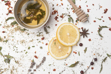 Herbal tea, top view. Dry herbs, lemon slices and tea cups on white. Herbs in bulk, zero waste and...