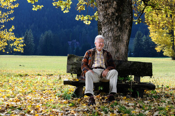 uomo anziano si riposa su una panchina nel parco di montagna