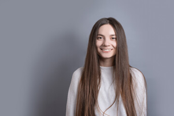 Fototapeta premium Pretty smiling joyfully female with dark hair, dressed casually, looking with satisfaction at camera, being happy. Studio shot of good-looking beautiful woman isolated against blank studio wall.