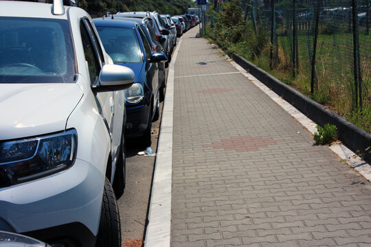 traffic and cars parked in a row along the road next to the tiled sidewalks on a sunny day