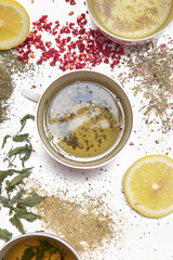 Herbal tea, top view. Dry herbs, lemon slices and tea cups on white. Herbs in bulk, zero waste and eco-friendly lifestyle, herbal medicine concept.