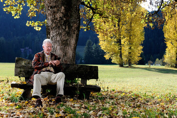 Uomo anziano seduto su una panchina in un sentiero di montagna