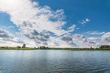 Panoramic landscape on a sunny day on the river, the sky in the clouds.