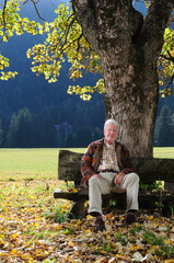 Ritratto di un uomo anziano seduto in un parco di montagna