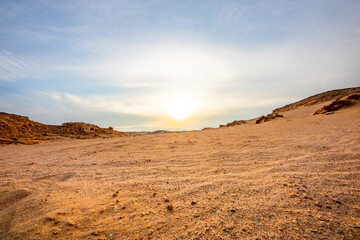 sand dunes and stones in the desert of Egypt at sunset with blue sky