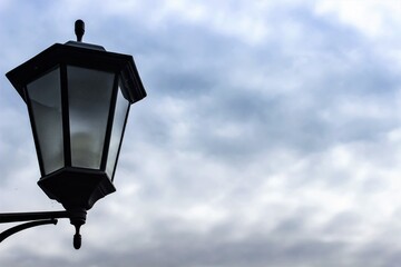 Fototapeta na wymiar Vintage lantern against a cloudy sky as an interesting backdrop.