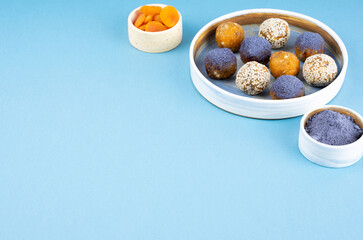 Homemade blue matcha butterfly pea tea powder energy balls in a ceramic bowl on a top view background, healthy sweets made of nuts, dry apricots, sesame. Concept vegeterian diet sweet brain food
