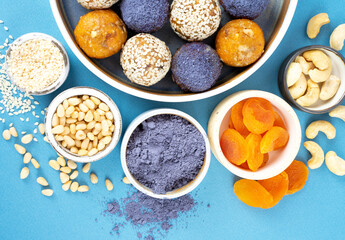 HomemaHomemade blue matcha butterfly pea tea powder energy balls in a ceramic bowl on a top view background, healthy sweets made of nuts, dry apricots, sesde blue matcha butterfly pea tea energy balls