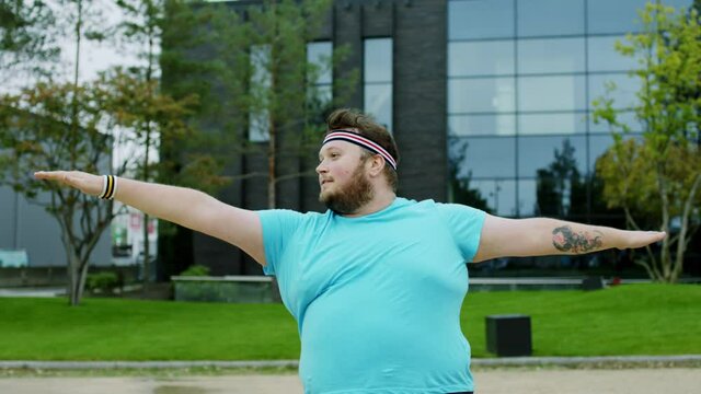 Yoga posing practicing obese man in front of the camera he stretching body outside beside of a modern building. 4k