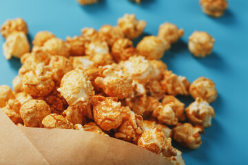Popcorn in caramel glaze in a paper envelope on a blue background.