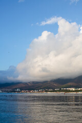 Fototapeta premium A huge white cloud over the sea and mountains