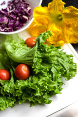 Vertical shot of organic salad ingredients. Fresh tomatoes, lettuce, cabbage and squash blossoms.