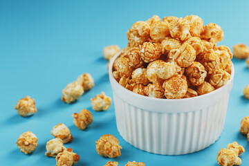 Caramel popcorn in a cup on a blue background, top view.