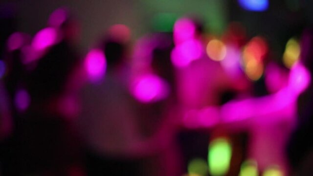 Blurred silhouettes of people dancing at a party in a nightclub. Soft focus, slow motion. Party with neon laser lights. Have fun tonight. Dance event