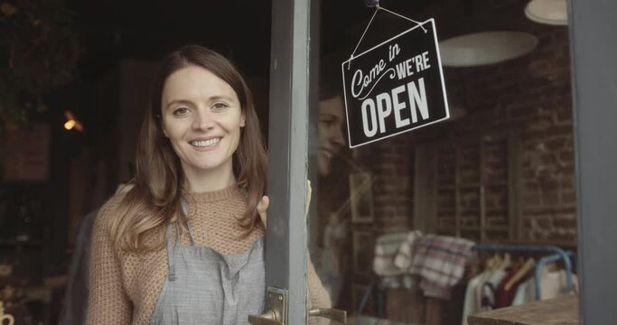 Portrait of female shop owner looking at camera after turning open sign
