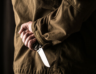 Man holding a knife behind his back
