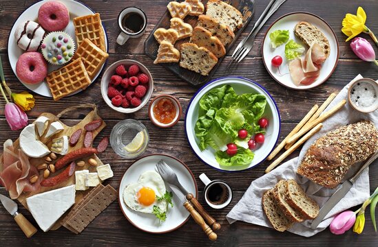 Breakfast food table. Festive brunch set, meal variety with charcuterie and cheese platter, fried egg, salad and various of desserts. Overhead view