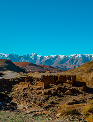 Vertical view of ancient ruins, landscapes, and snow-capped mountains in the Atlas Mountain Range in Morocco