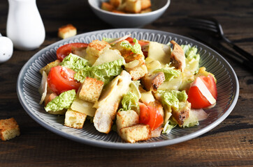 Caesaor salad. Salad with romaine leaves, chicken and tomans in a plate. Horizontal focus.