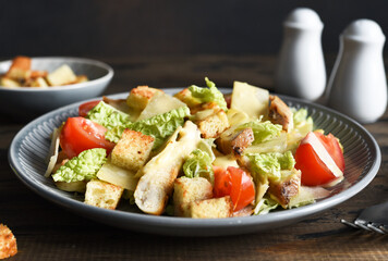 Caesaor salad. Salad with romaine leaves, chicken and tomans in a plate. Horizontal focus.