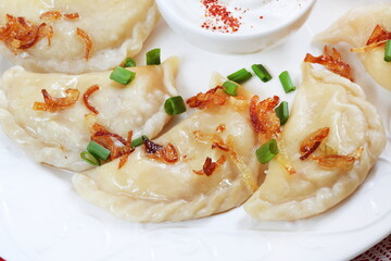 Dumplings with potatoes and sour cream on a white plate