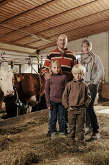 Ritratto di una famiglia di contadini dentro la fattoria con le mucche