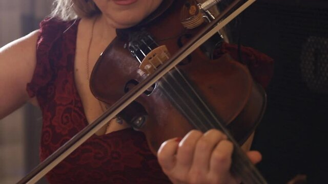violinist playing violin during a music concert. close-up. violinist performance on stage, light, dark background.