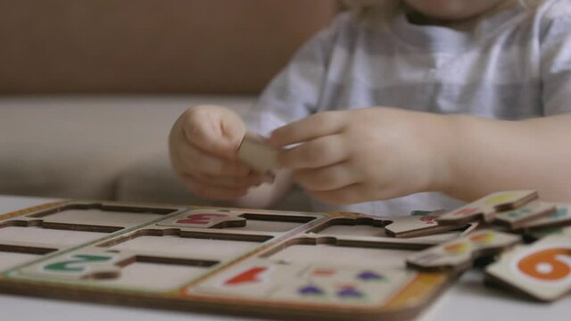 Little girl playing puzzel with numbers on the table. Figures. Handheld close up shot.