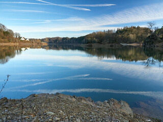 The Wuppertalsperre reservoir with a dam on the Wupper River. In the center of the frame, a small island in the middle of the lake. A beautiful reflection of the sky in the water. Wonderful landscape