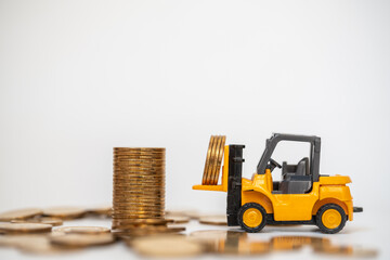 Business, Money and Financial Concept. Closeup  mini forklift truck mini car toy model contain coins to stack of gold coins on white background.