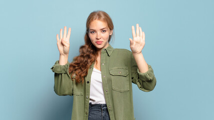 blonde pretty woman smiling and looking friendly, showing number nine or ninth with hand forward,...